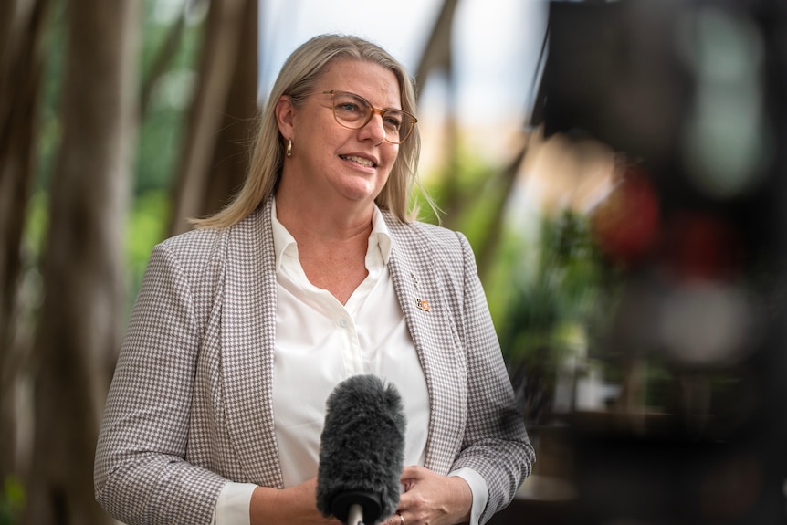 A woman in a white shirt and checked blazer