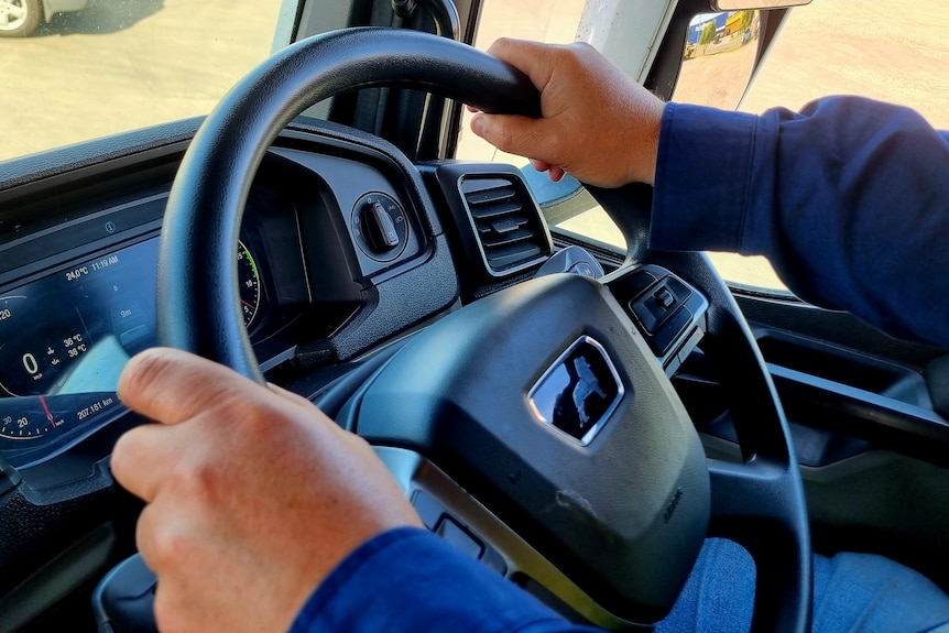 Two hands on a steering wheel.