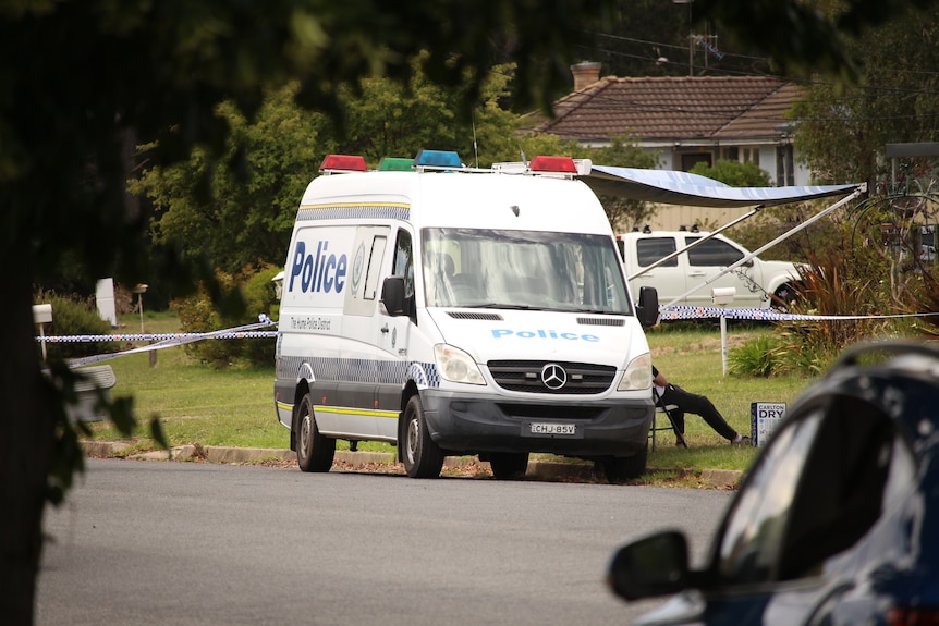 A police van sits on the street outside a house.
