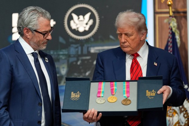 President Donald Trump listens as Casey Wasserman, chairman of LA28, presents him a full set of medals from the 1984 Olympics in Los Angeles, during an event regarding the 2028 Los Angeles Olympic Games, in the South Court Auditorium of the Eisenhower Executive Office Building on the White House campus, Tuesday, Aug. 5, 2025, in Washington. (AP Photo/Alex Brandon)