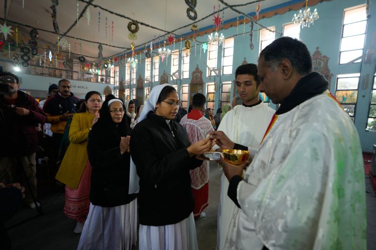 An Indian Christian woman receives holy communion as others wait in a queue during Christmas at St. Mary's Garrison church, in Jammu, India, Thursday, Dec.25, 2025. (AP Photo/Channi Anand)