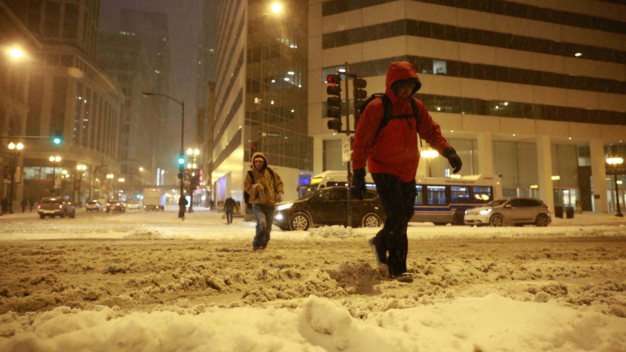People trudge through newly fallen snow as they cross Michigan...
