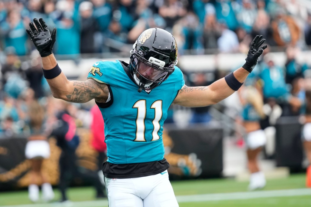 A Jacksonville Jaguars player wearing number 11 raises his arms in celebration.