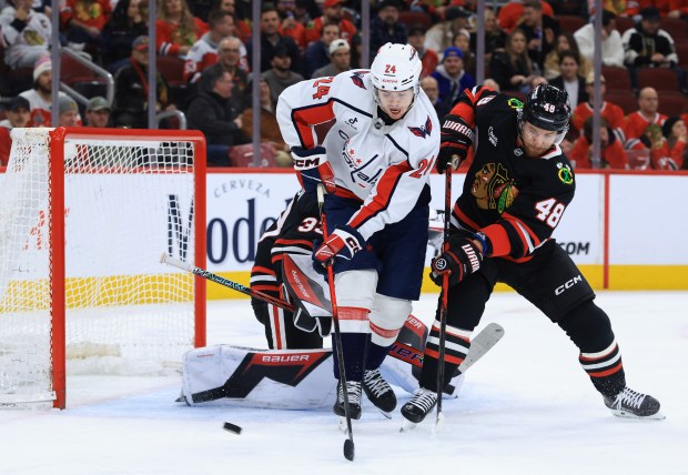 Capitals center Connor McMichael (24) and Blackhawks defenseman Matt Grzelcyk (48) reach for the puck in the second period at the United Center on Jan. 9, 2026, in Chicago. (John J. Kim/Chicago Tribune)