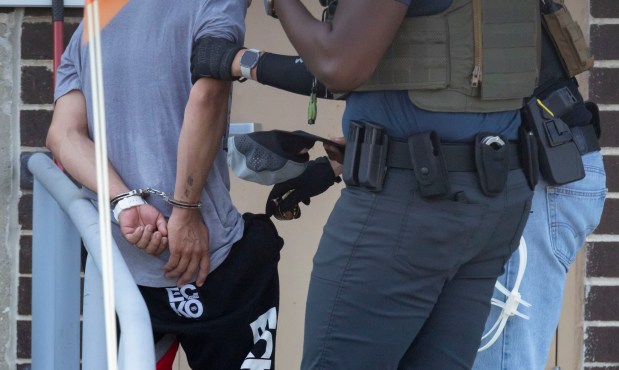 Federal agents search a detainee Sept. 28, 2025, while escorting him into the U.S. Immigration and Customs Enforcement facility in Broadview. (Brian Cassella/Chicago Tribune)