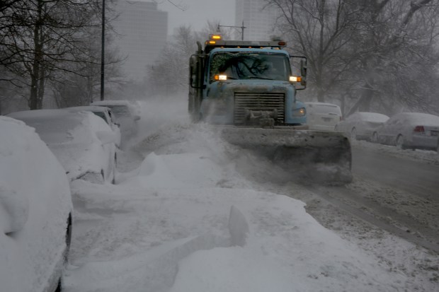 A snowplow piles more snow on top of parked cars on Stockton Drive in Chicago on Feb. 1, 2015. (Nancy Stone/Chicago Tribune)