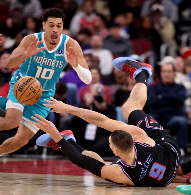 Chicago Bulls center Nikola Vučević (9) lays on the ground as he passes the ball by Charlotte Hornets guard Josh Green (10) in the second half of a game at the United Center in Chicago on Jan. 3, 2026. (Chris Sweda/Chicago Tribune)