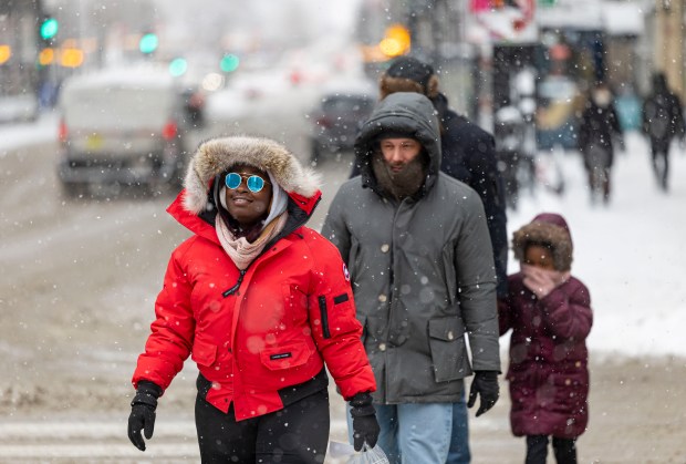 People walk along North Michigan Avenue while snow falls on Jan. 25, 2026, as cold weather continues in Chicago's Loop. (Brian Cassella/Chicago Tribune)