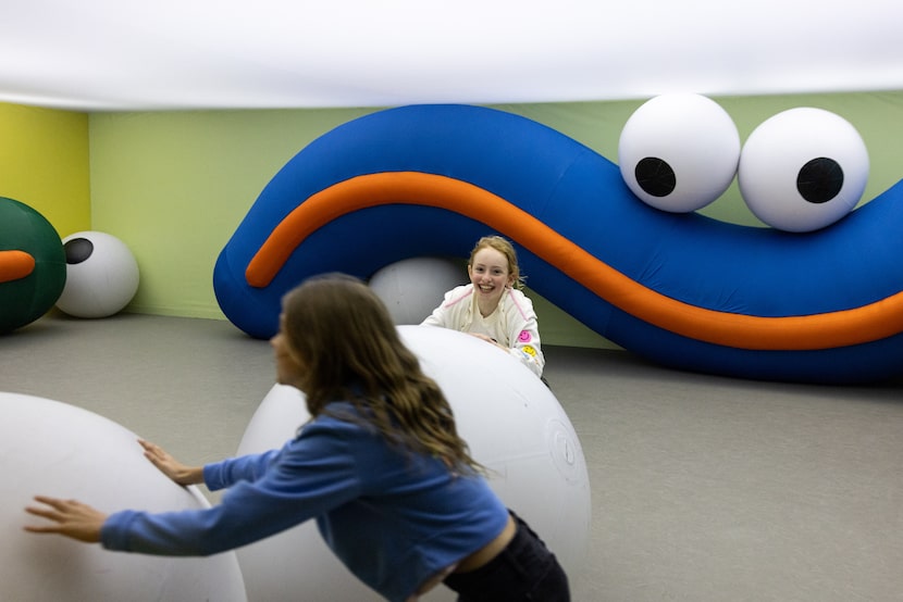 Simone Cox, front, and friend Lucia Sardone play with inflated balls in the “Squeezed In”...