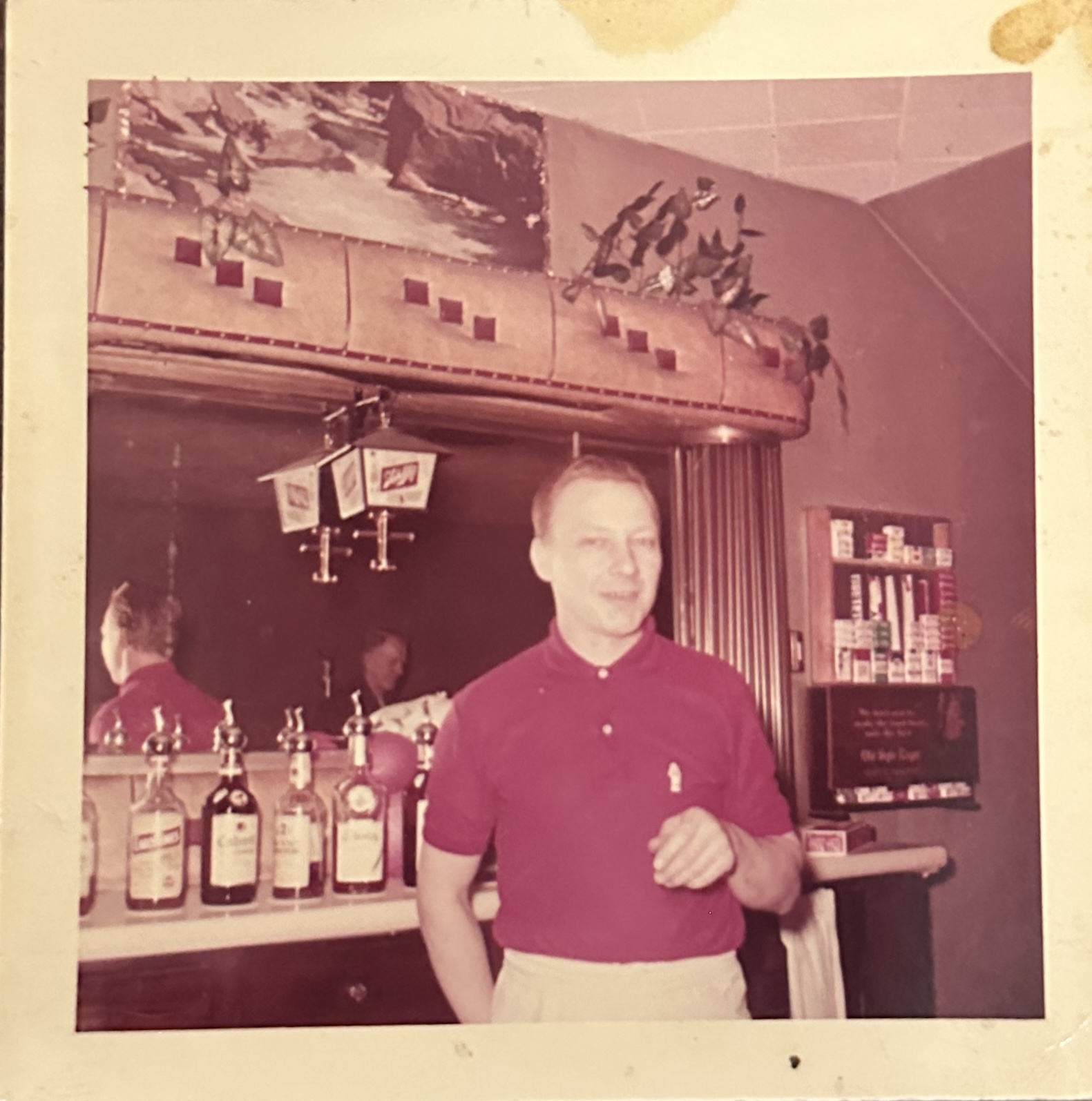 The upholstered back bar is on view in this retro photo of a bartender at Belmont Tavern.