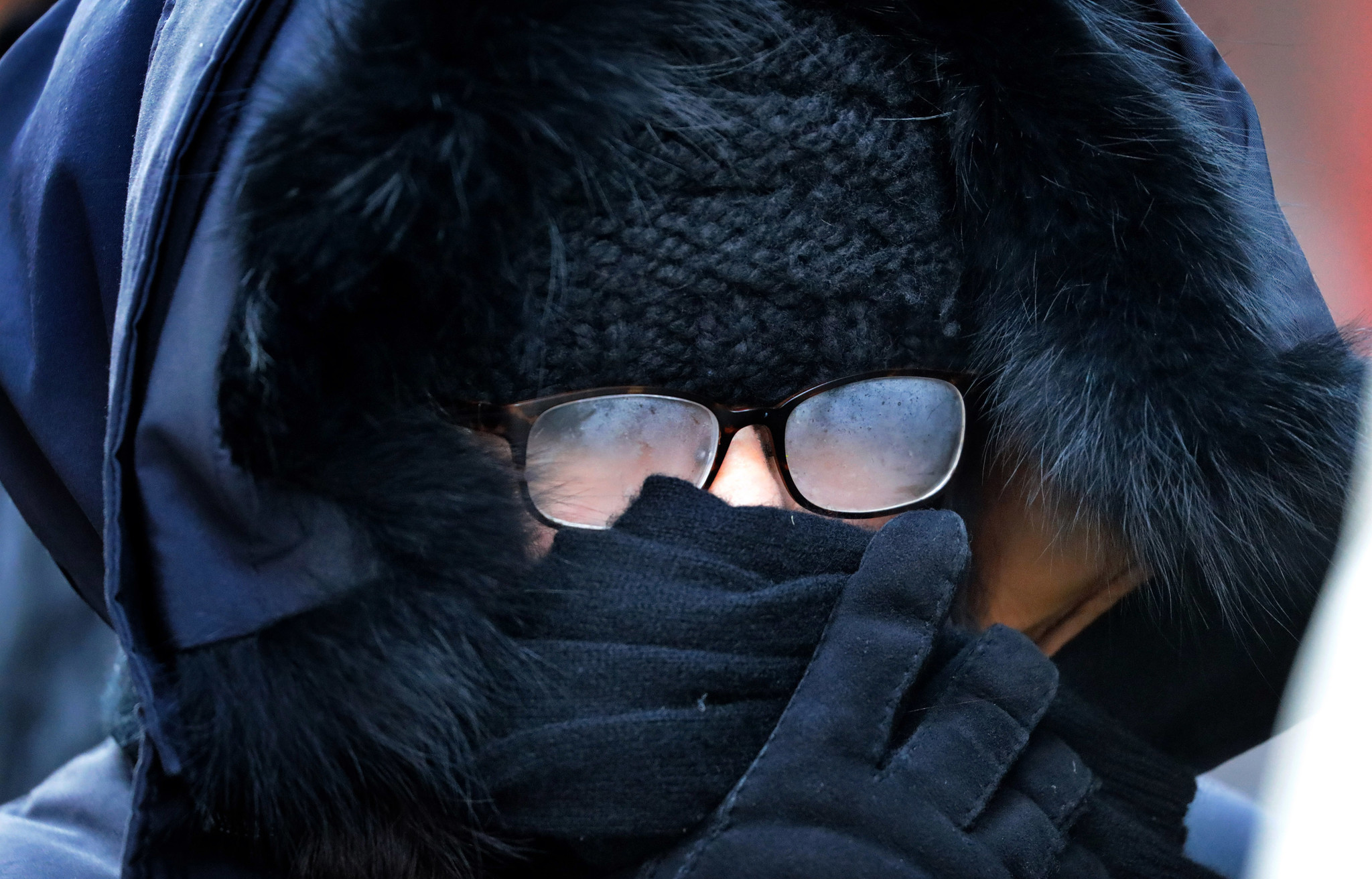 A woman's glasses fog up while covered up in layers...