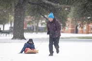 Nathaniel Maratas pulls son Ethan Maratas, 7, around on a makeshift sled in the snow at...