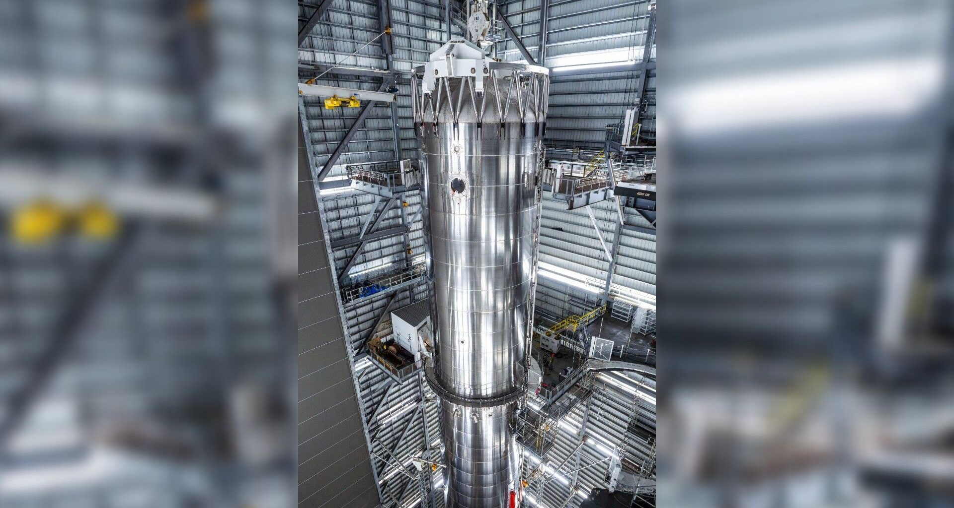 a tall silver rocket upright in a hangar
