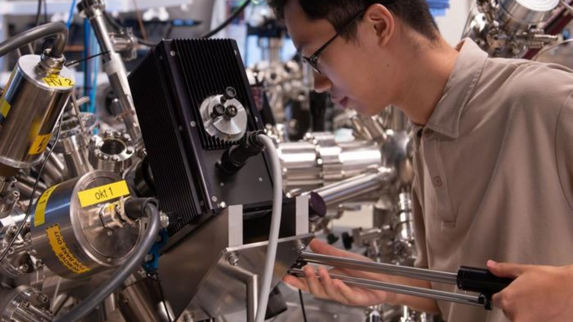 The time- and angle-resolved photoemission spectroscopy (TR-ARPES) setup at OIST, here with study co-first author Xing Zhu, PhD student in the Femtosecond Spectroscopy Unit. Featuring a proprietary, table-top extreme-UV source emitting bursts at femtosecond intervals (1fs = one millionth of one billionth of a second), this setup captured the first real images of excitons, helped sketch out the evolution of dark excitons, and has now proved the feasibility of excitonic Floquet engineering.