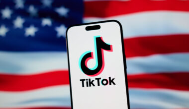 The TikTok app and logo are seen on a mobile device in front of a US flag