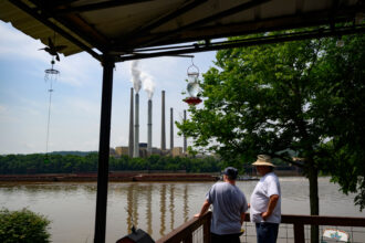 Trent Williams and his grandson, Nathan, look across the Ohio River at the Hugh L. Spurlock Generating Station on June 12 in Maysville, Ky. Credit: Jeff Swensen/Getty Images