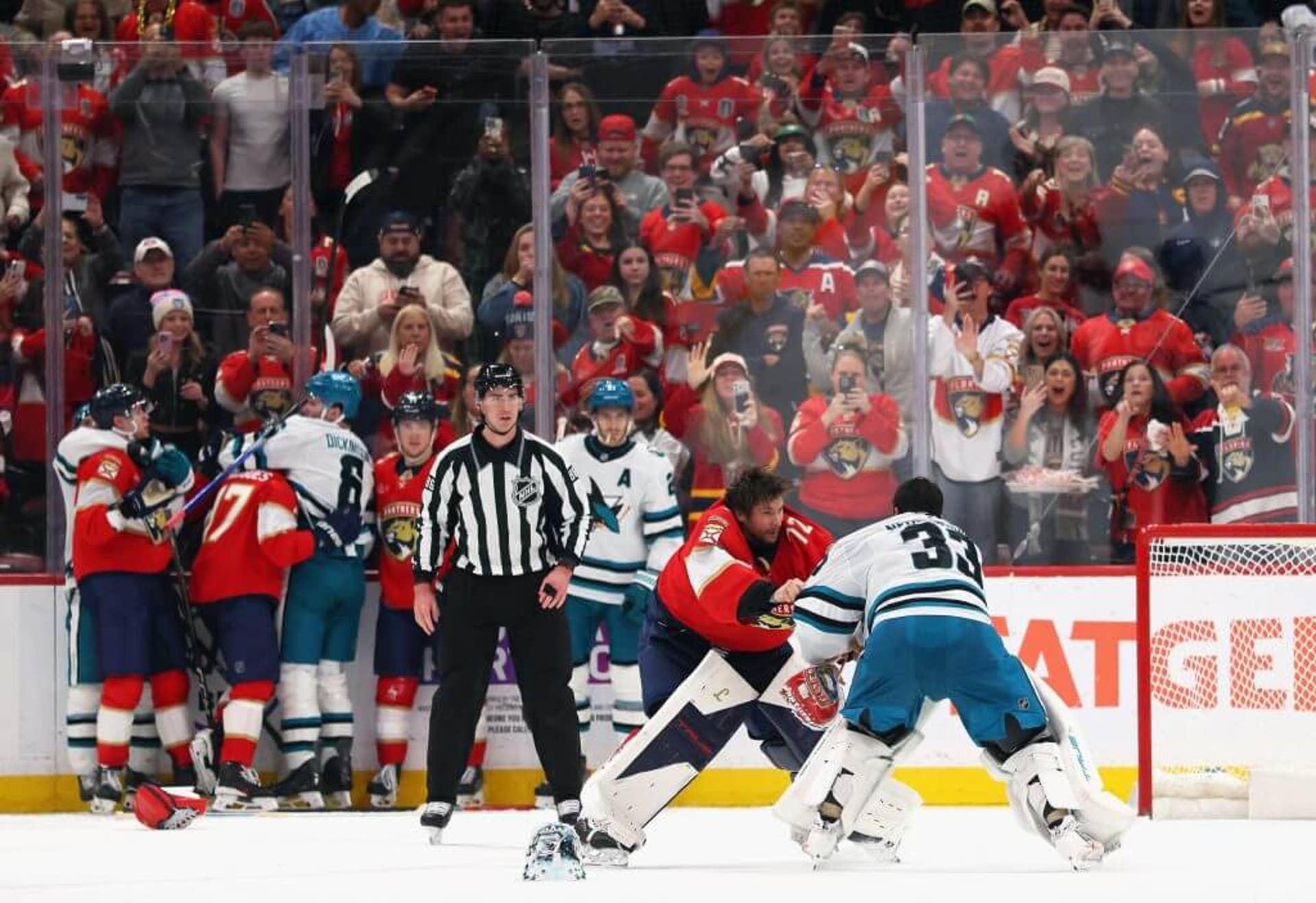 Goalies Sergei Bobrovsky and Alex Nedeljkovic trade blows with a ref looking on and Panthers and Sharks players jostling behind the ref.