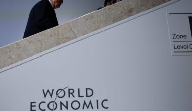 A woman stands in a target with her fist in the air. A man behind her holds an "Abolish ICE" sign.