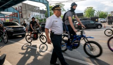 Philadelphia Police Commissioner Kevin Bethel walks through Kensington, flanked by bicyclists.