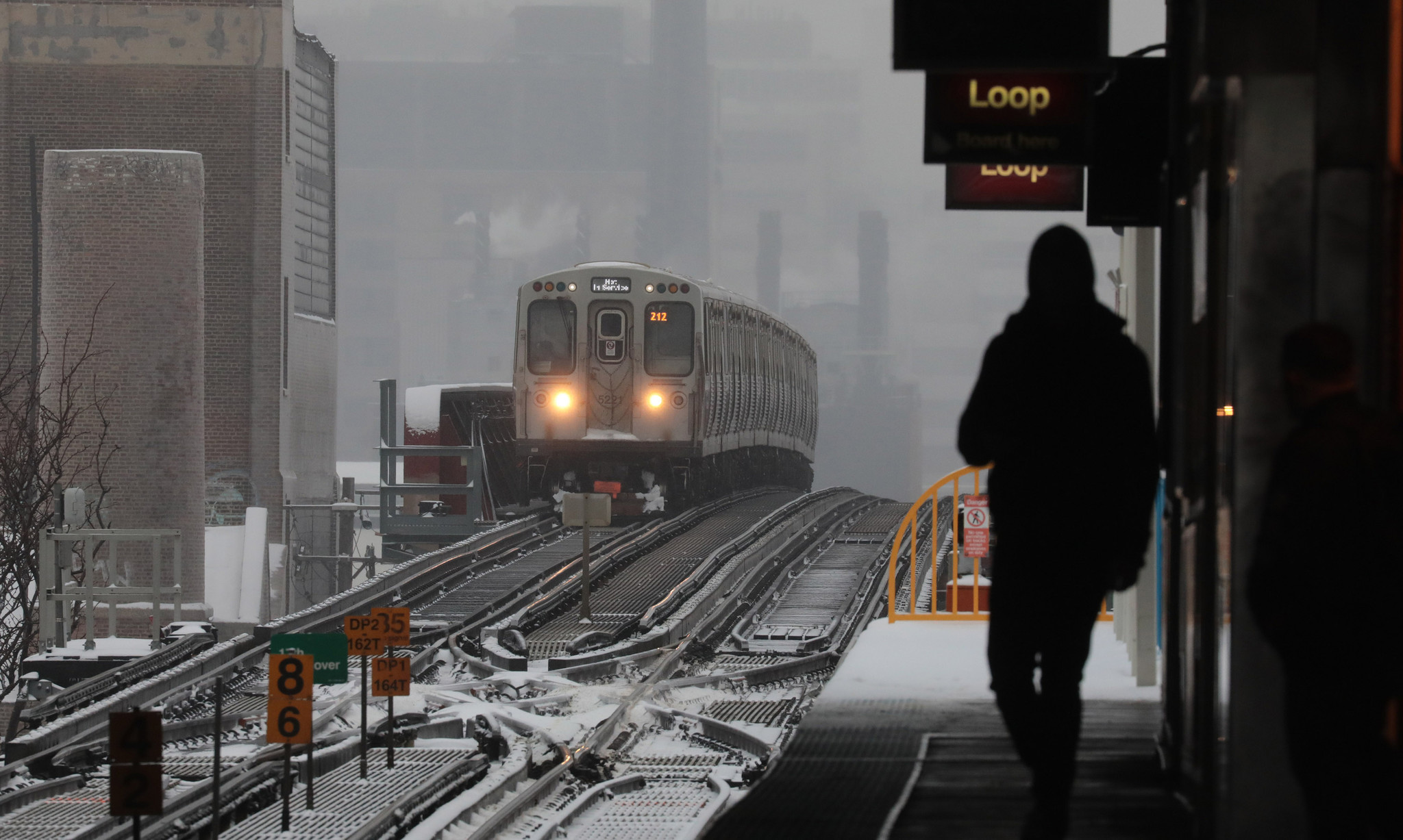 Commuters await their trainÂ at the CTA's Pink Line Damen station...