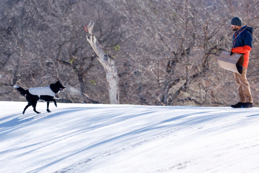 Stefan Nelson, 38, watches as his dog Kira, 7, makes her way up an icy hill at Trinity Park,...