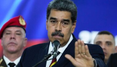 Men watch smoke rising from a dock after explosions were heard at La Guaira port, Venezuela, Saturday, Jan. 3, 2026. (AP Photo/Matias Delacroix)