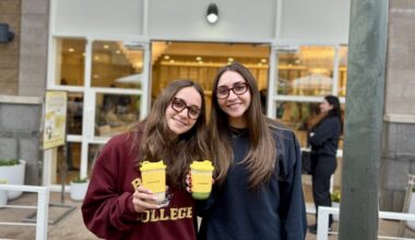 Two women hold coffees from La La Land Kind Cafe.