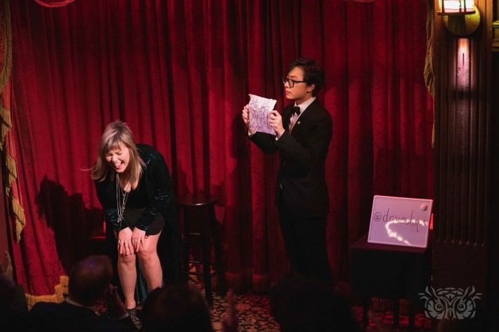 a young magician holds a piece of paper with a Chinese character written on it