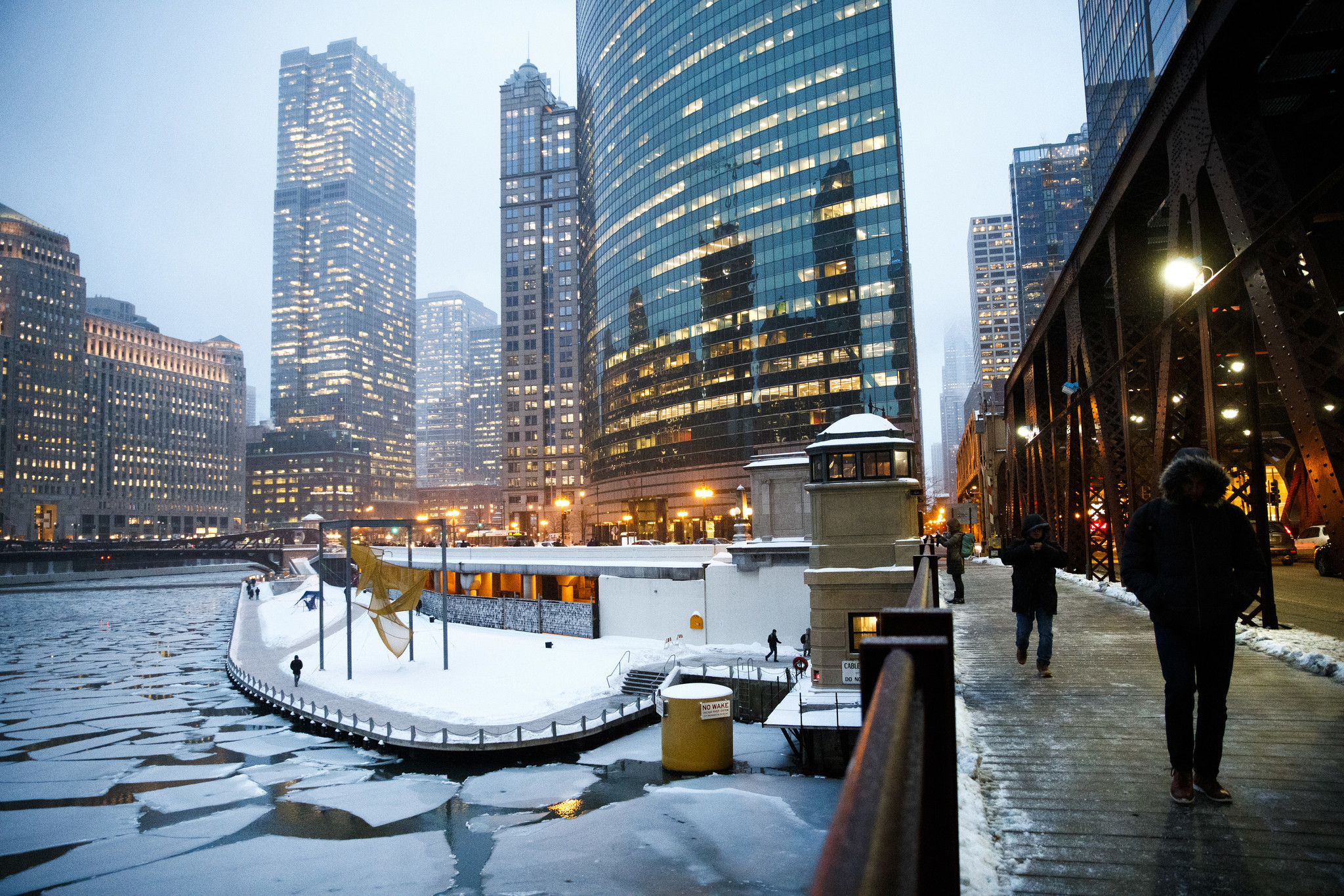 Pedestrians cross Lake Street bridge while sheets of ice cover...