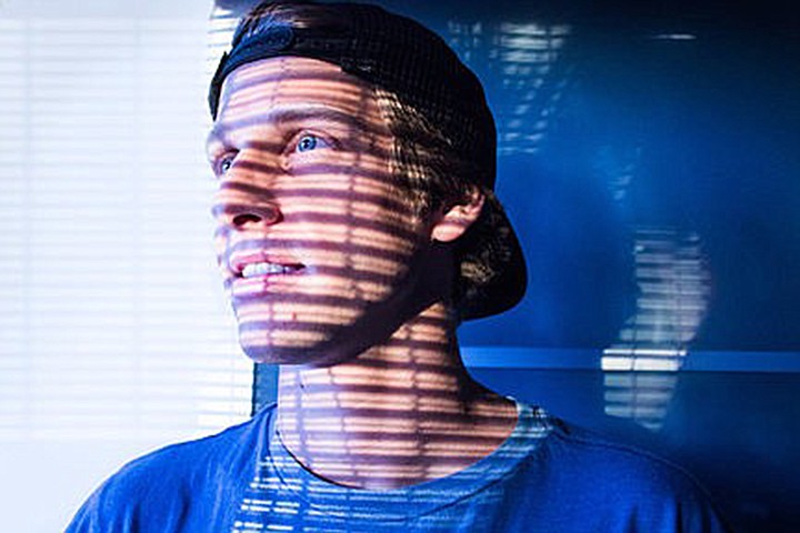 Head shot of man wearing baseball cap with shadows across face
