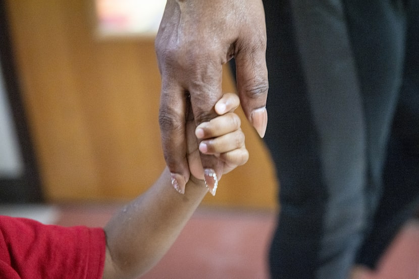 Toddlers teacher Angela Nails holds 1-year-old Jayden White’s hand while a group of students...