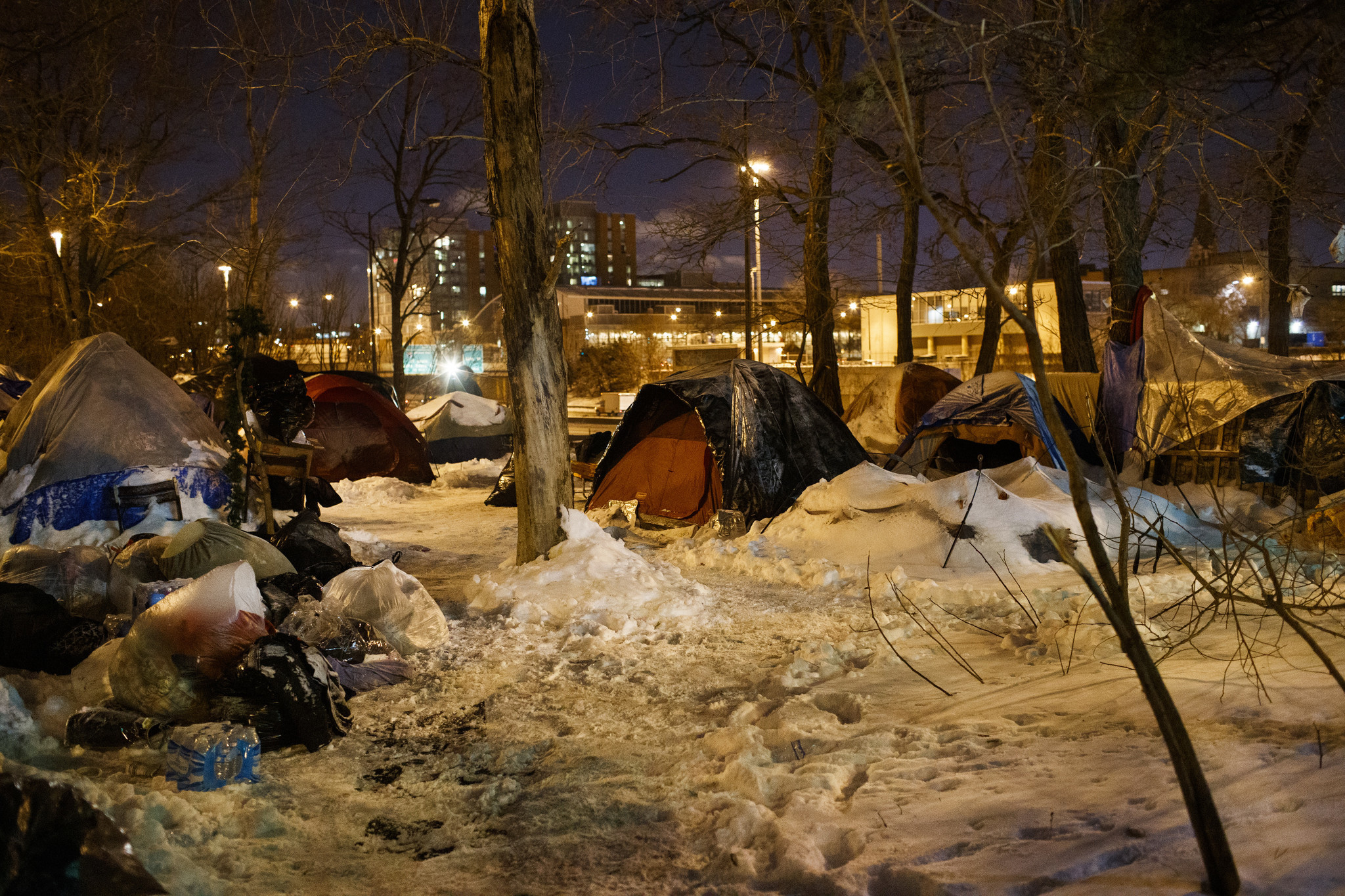A person walks between tents while people sleep near a...