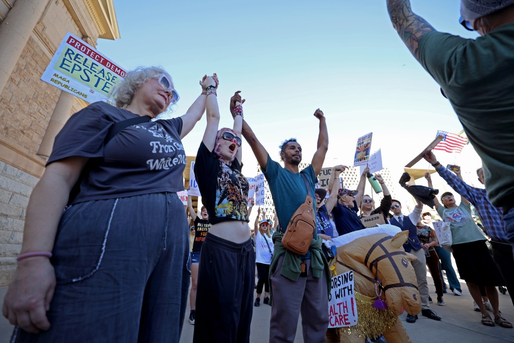 Protestors raise their arms in unity at the Arizona Capitol on Jan. 20, 2026. 