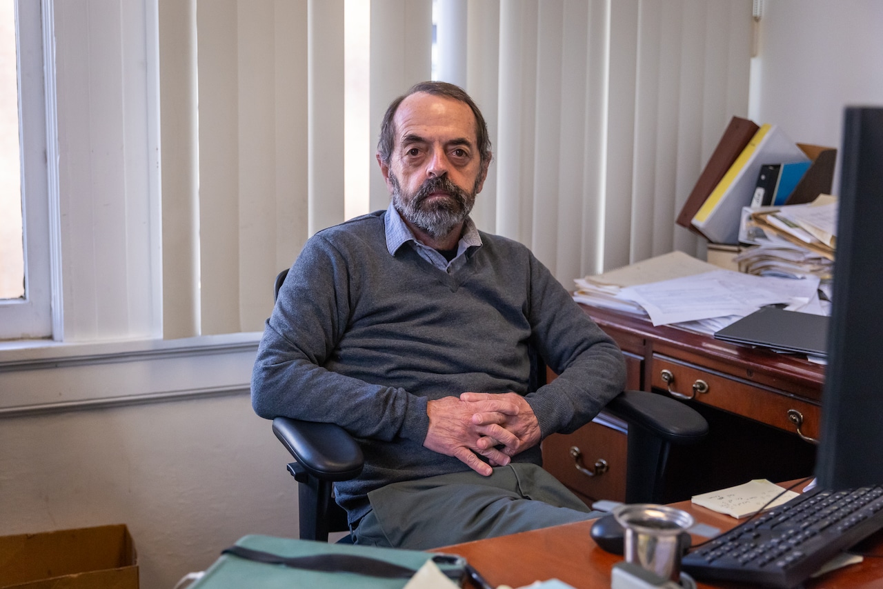 A man poses for a photo at his desk