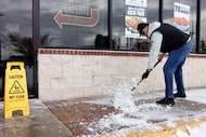 Wing Stop general manager Daniel Rodriguez shovels ice from a sidewalk outside the...