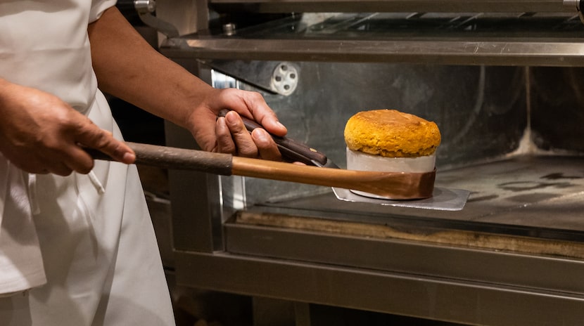 Chef Alberto Solis takes a Frito Chili Soufflé out of the oven using a hook.