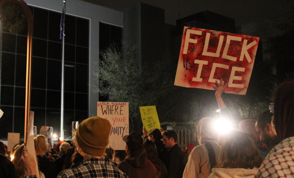 people hold signs, including one that says "fuck ice"