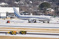 Airport workers clear snow as the Dallas Mavericks Boeing 757 sits at Dallas Love Field...