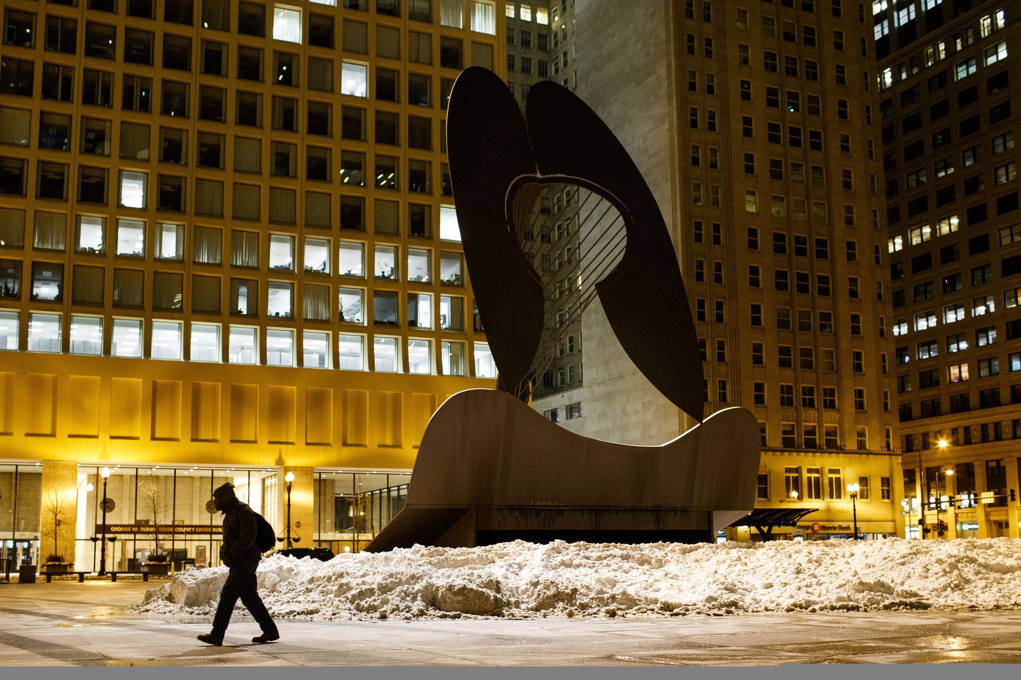 A man walks by the Picasso statue in the Loop...