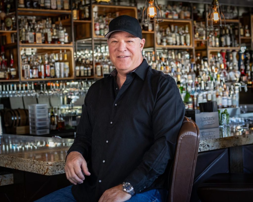 A man sitting at a stool in abar