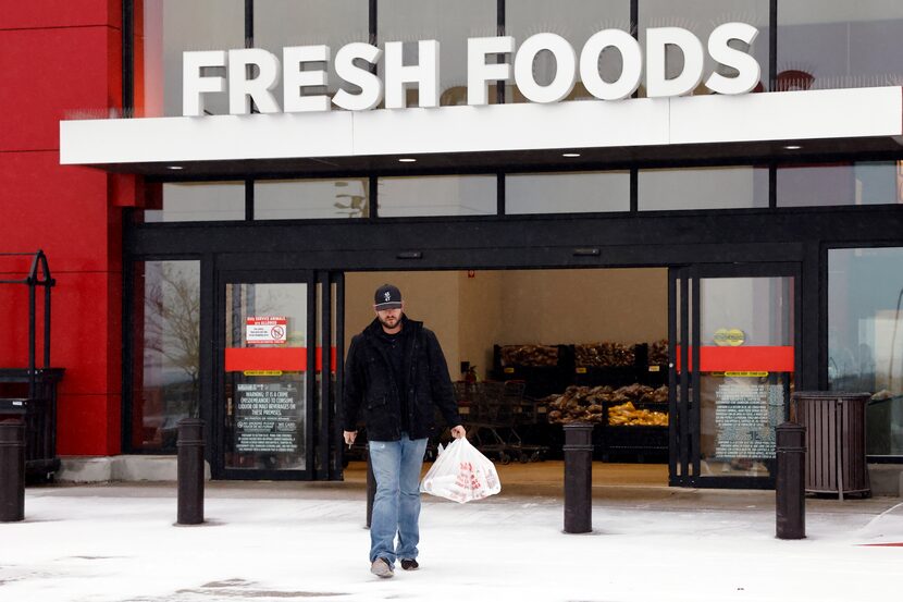 Mike Turner carries a handful of groceries as he walks to his car over an icy parking lot...