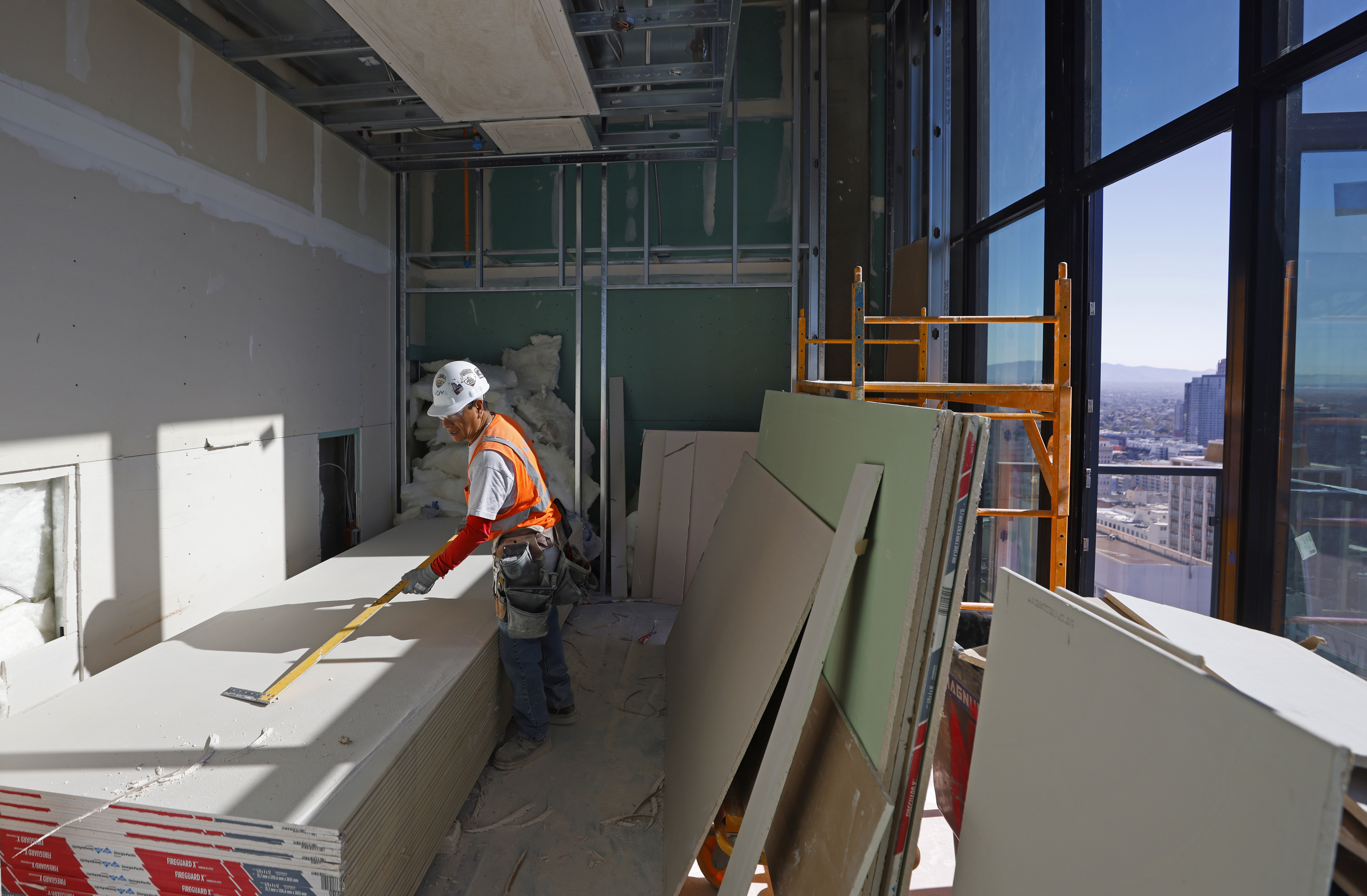 A worker measures drywall in a penthouse in The Torrey....