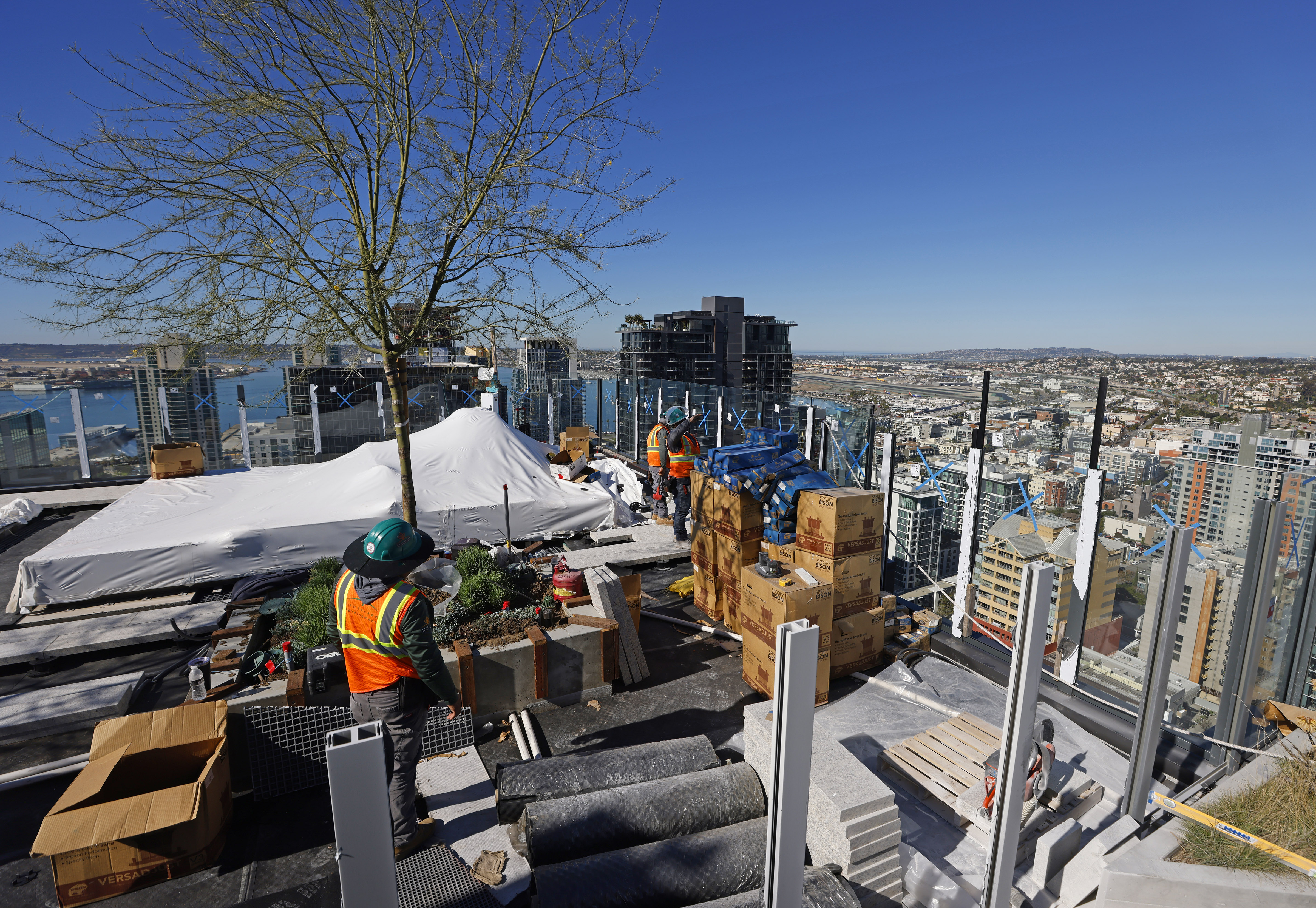Workers work on the rooftop pool deck of The Torrey,...
