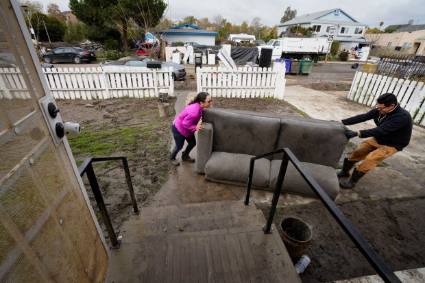 Jose and his wife Martha Navarro move wet furniture out of their home after historic floods devastated the house on Beta Street in Southcrest in January 2024. (Nelvin C. Cepeda / The San Diego Union-Tribune)