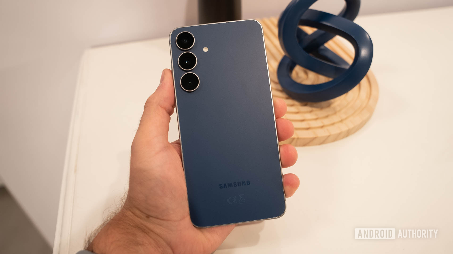 Samsung Galaxy S25 FE in Navy in man's hand showing back of phone