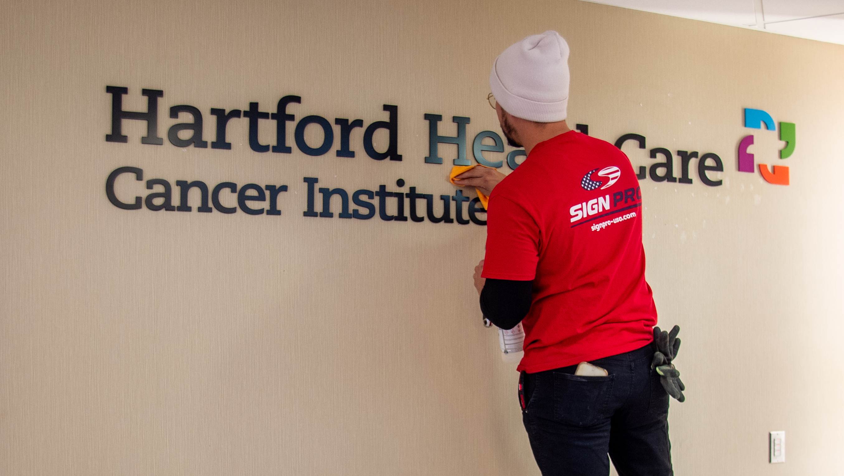 Emmanuel Rivera of Sign Pro hangs a new Hartford HealthCare...