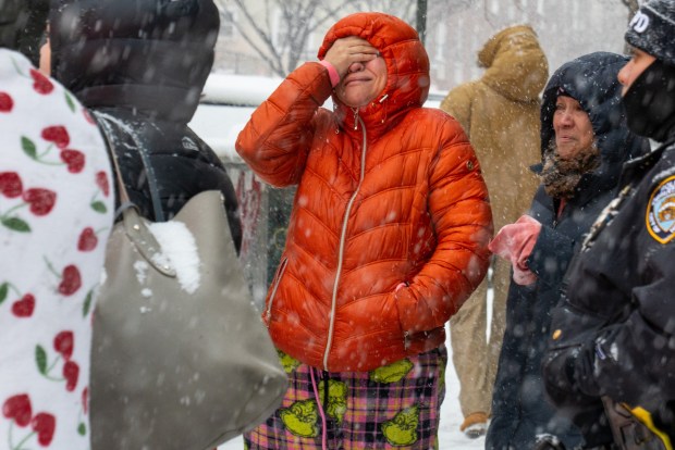 People cry at the scene after a 50-year-old woman was killed in a Bronx apartment fire on Sunday.