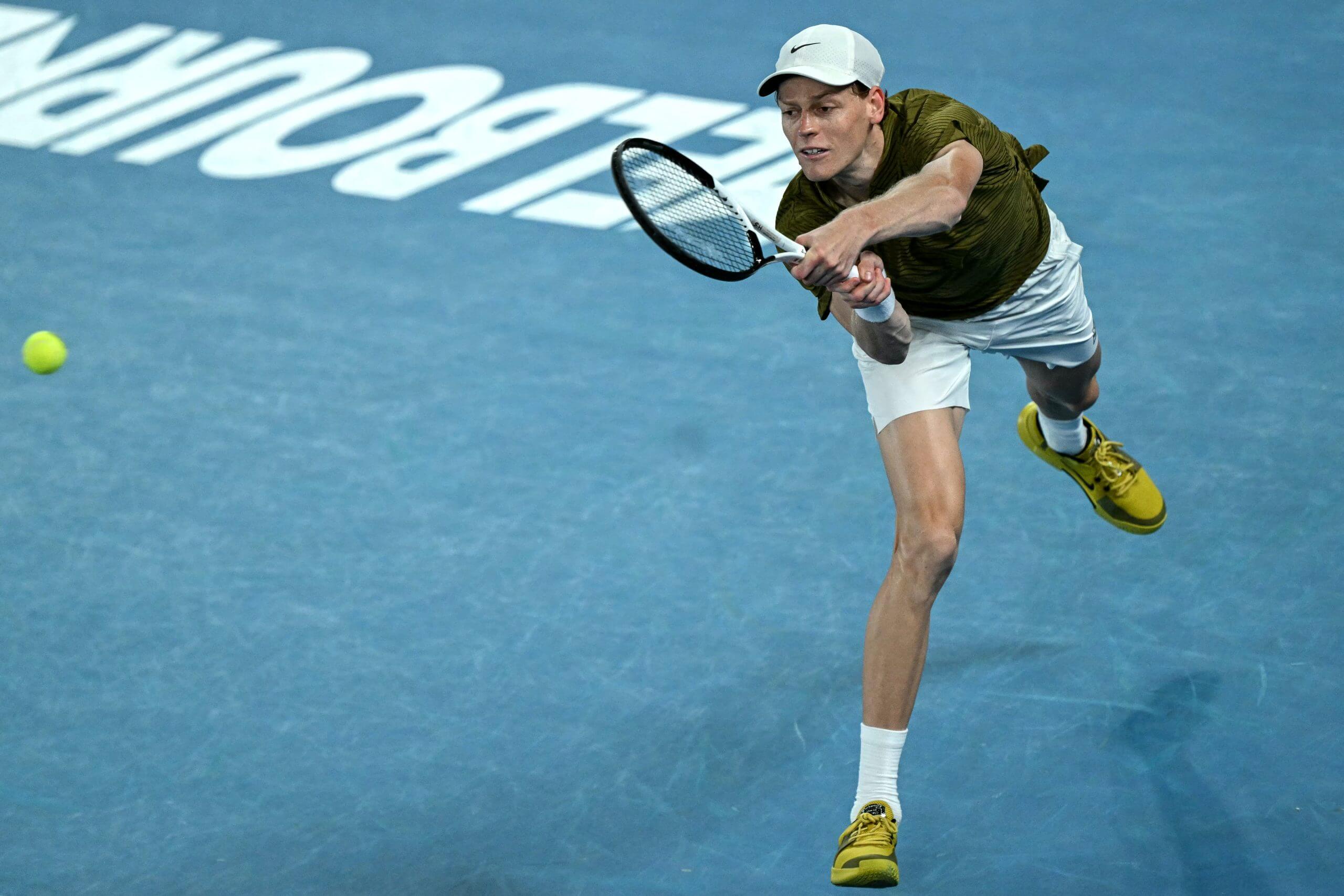 Jannik Sinner stretches to return a ball on a blue court with the word Melbourne in white in the background