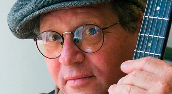 Close up of man wearing glasses and cap and holding guitar