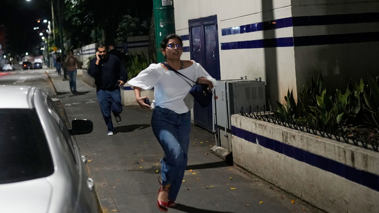 Pedestrians run after explosions and low-flying aircraft were heard in Caracas, Venezuela, Saturday, Jan. 3, 2026. (AP Photo/Matias Delacroix)